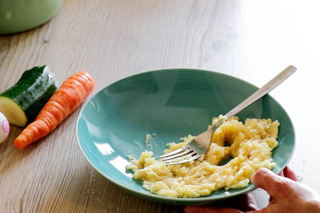 BLW Rezept Dinkelvollkorn Pancakes Frau zerdrückt Banane im Teller