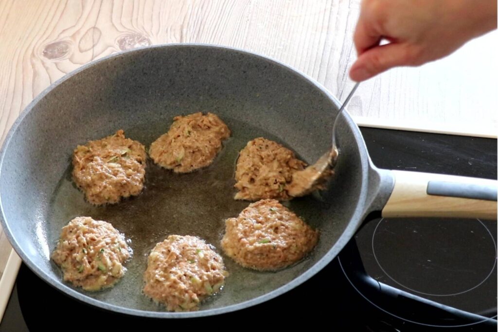 Baby Led Weaning Rezept Dinkelvollkorn Pancakes Frau gibt jeweils einen Esslöffel des Teigs in Bratpfanne nun sind 6 Pancakes in der Bratpfanne